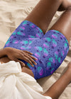 Model lounging in sand in galaxy cat yoga shorts, emphasizing soft, breathable fabric