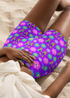 Model lounging in 70’s floral yoga shorts in purple, emphasizing soft, stretchy fabric.