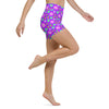 Model in motion wearing high-waisted yoga shorts with vibrant purple 70’s floral design.