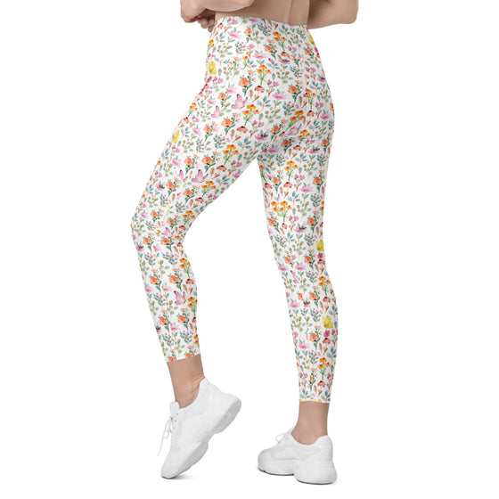 Model walking in high waisted spring floral leggings with bees and butterflies. Women's compression leggings with pockets for yoga, walks, or errands.
