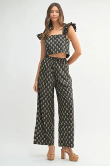  Woman wearing a black floral print co-ord set featuring a breezy top and matching pants, styled for an elegant front-facing fashion look.