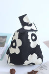 Side view of the black flower-knitted handbag, showcasing its sleek design and colorful floral details in black.

