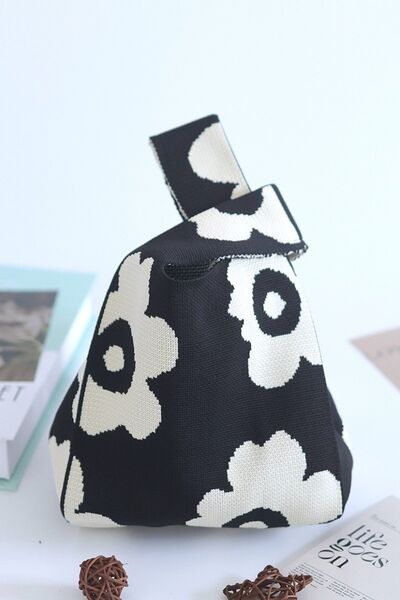 Side view of the black flower-knitted handbag, showcasing its sleek design and colorful floral details in black.


