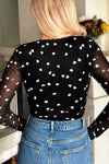 Back view of the bodysuit on the model, emphasizing the mesh back coverage, seamless bottom fit, and overall romantic transparency of the heart pattern.

