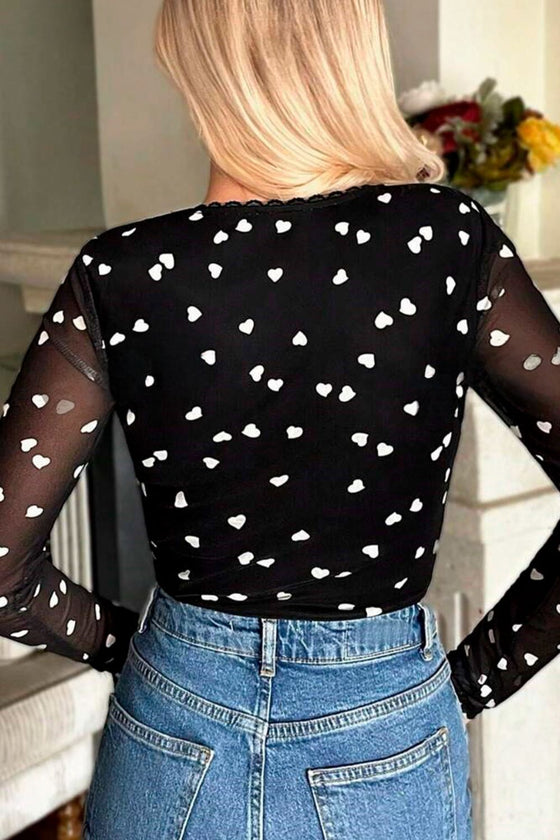 Back view of the bodysuit on the model, emphasizing the mesh back coverage, seamless bottom fit, and overall romantic transparency of the heart pattern.


