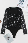 Laid-flat front image of the black bodysuit showing its intricate heart print mesh, clean neckline finish, and tailored structure for a secure yet feminine fit.

