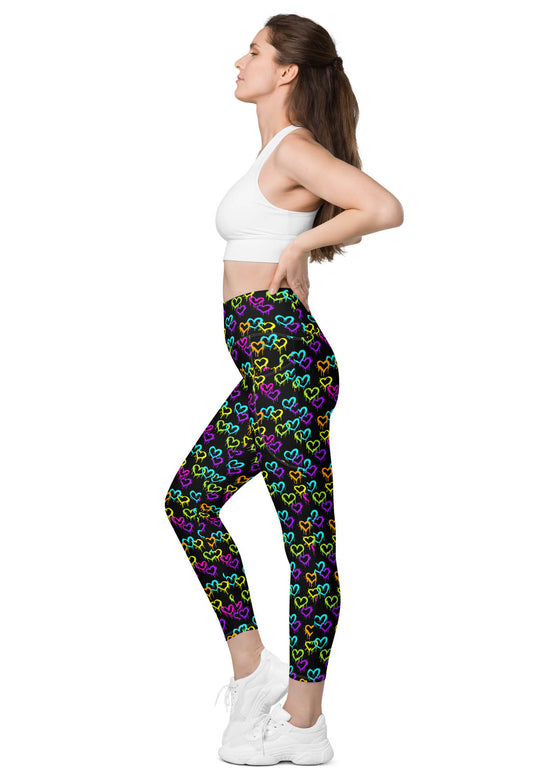 Side view of a woman wearing Black Rainbow Melting Hearts High-Waisted Leggings with pockets, offering mild compression and support for workouts and yoga.