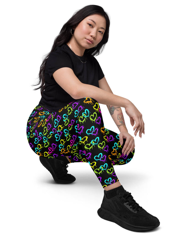 Side view of a woman sitting, wearing Black Rainbow Melting Hearts Compression Leggings for women, highlighting a sculpting high-rise fit with sweat-wicking fabric.