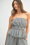 A close-up of the peplum top, highlighting the checkered pattern, curved bust seam, and cinched waist detailing for a feminine silhouette.

