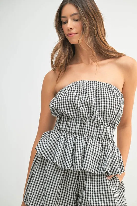 A close-up of the peplum top, highlighting the checkered pattern, curved bust seam, and cinched waist detailing for a feminine silhouette.

