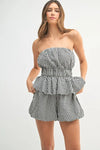 A stylish full front image of the black and white gingham co-ord set featuring a fitted peplum top with a sweetheart neckline and matching high-waisted shorts.


