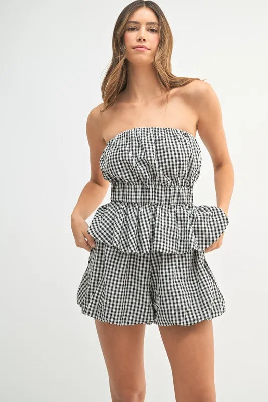 A stylish full front image of the black and white gingham co-ord set featuring a fitted peplum top with a sweetheart neckline and matching high-waisted shorts.

