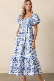  Model wearing the Blue Smocked Printed Puff Sleeve Dress in a full front standing pose. The smocked bodice, floral print, and puff sleeves give it a soft, romantic vibe.