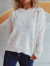 Woman wearing a Bow Trim Round Neck Long Sleeve Sweater with delicate bow details, styled with dark jeans for a chic and cozy look.

