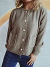 Woman wearing a button-up long sleeve cardigan with functional pockets, styled with dark jeans for a casual yet chic look.

