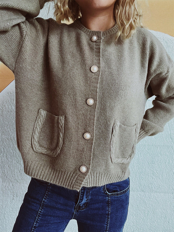 Woman wearing a button-up long sleeve cardigan with functional pockets, styled with dark jeans for a casual yet chic look.

