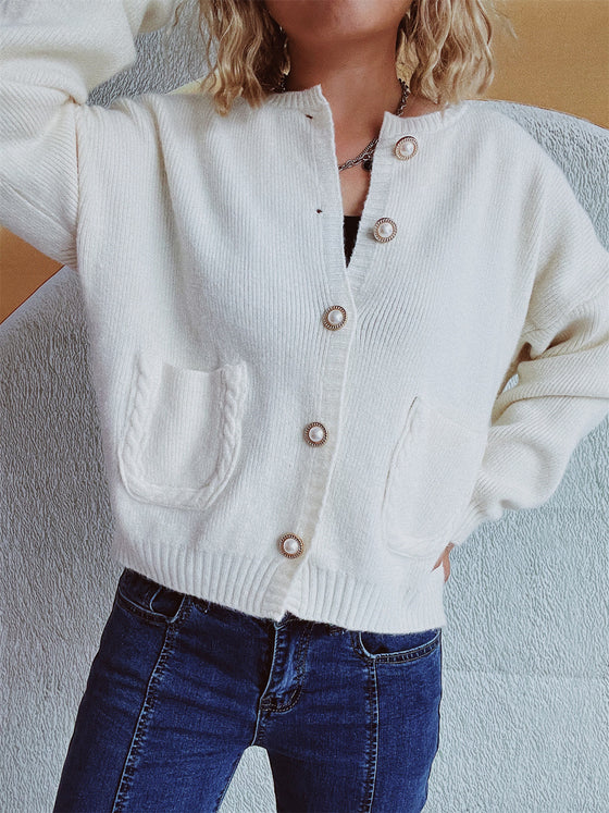 Woman wearing a button-up long sleeve cardigan with functional pockets, styled with dark jeans for a casual yet chic look.

