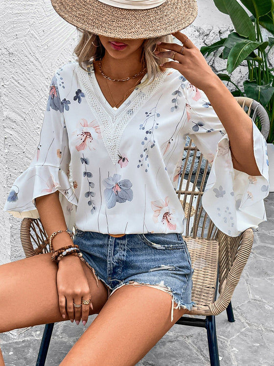 Front view of a relaxed-fit white blouse featuring soft floral prints and half sleeves, ideal for workwear or daytime wear.