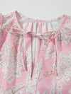 Detailed neckline close-up of the pink blouse, showing floral print and gentle gathers along the rounded neck.