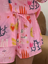  Closeup of the front of the pink printed skirt from the outfit set, highlighting the fine floral patterns, front buttons, and light summery fabric texture.

