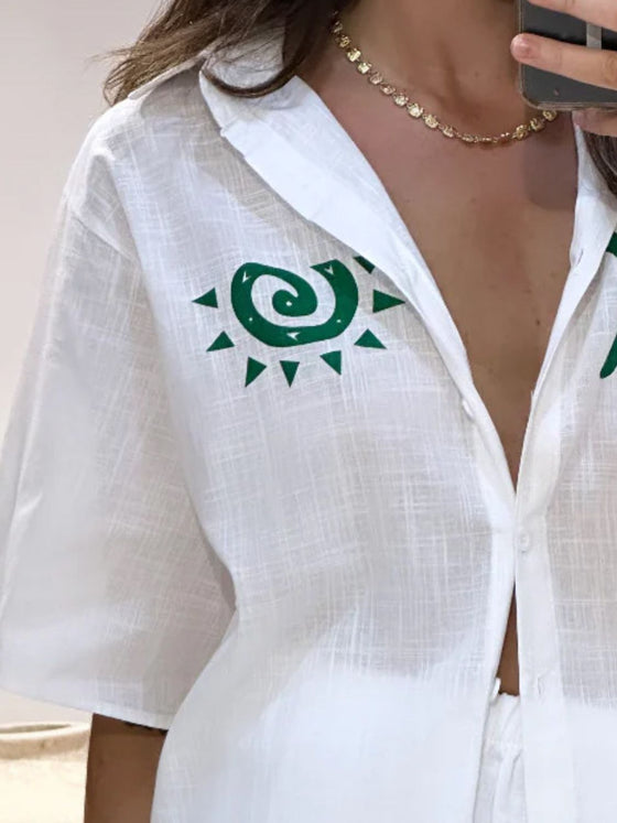 Closeup shot of the front of the white printed button-down shirt, showcasing the neat collar, lightweight fabric, and delicate summer-inspired prints.

