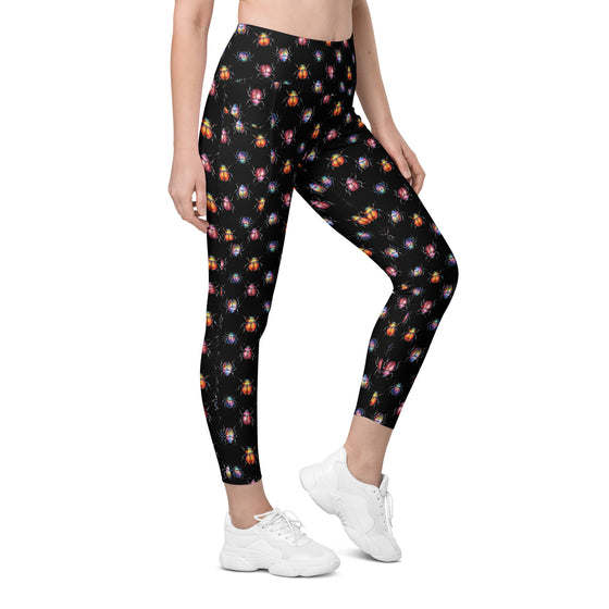 Model wearing Cori Michelle high waist leggings in black with beetle bug print. Stylish compression leggings for women with side pockets.