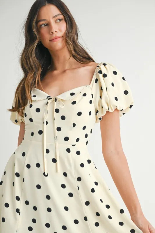  Front close view of cream midi dress with puff sleeves and subtle polka dots highlighting soft textures and neckline design.