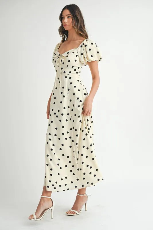 Side view of cream midi dress with dotted pattern and puff sleeve detailing, highlighting the relaxed fit and elegant flow.