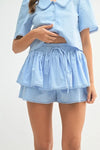 Matching crop top and shorts set in sky blue, styled with simple lines and soft tailoring for a trendy front pose.
