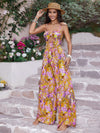 Woman wearing a vibrant printed spaghetti strap jumpsuit with a front cutout and wide-leg design, ideal for summer outings.