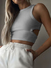 Model wearing a Cutout Round Neck Tank paired with white joggers, showcasing its trendy cutout design and flattering round neckline.

