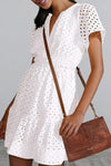 Woman wearing the Eyelet Notched Short Sleeve Mini Dress, styled with summer accessories for a casual outing.