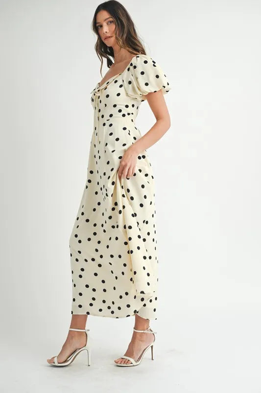 Cream dot-print midi dress captured from the side to emphasize the airy puff sleeves and flowing silhouette.