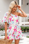 Woman wearing a floral asymmetrical neck romper with a belted waist and puff sleeve, ideal for casual outings and summer events.