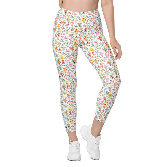 Full front pose of woman wearing white leggings with spring floral, bee, and butterfly design. Stylish high waist leggings with pockets for active women.
