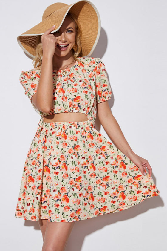 Woman wearing a floral mini dress with a cutout waist, puff sleeves, and a round neckline, ideal for casual summer outings.