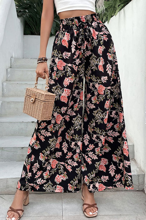 Woman wearing floral pull-on wide-leg pants with a bold floral pattern against a black background, featuring an elastic waistband and flowing silhouette, perfect for casual outings.