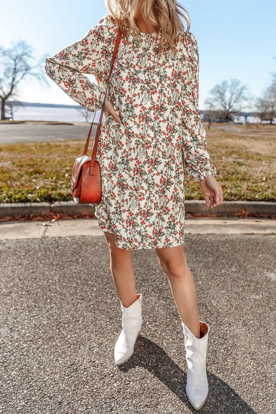 A lifestyle shot of a woman wearing the Floral Round Neck Long Sleeve Mini Dress, styled with a crossbody bag for a casual day out.
