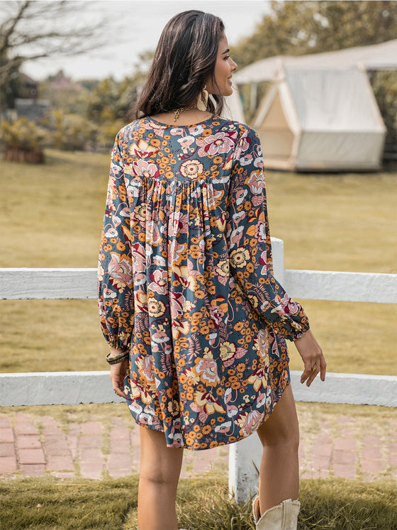 Back view woman in a dark floral ruched V-neck dress with long sleeves, showcasing boho-inspired style.