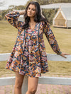 Woman in a dark floral ruched V-neck dress with long sleeves, showcasing boho-inspired style.