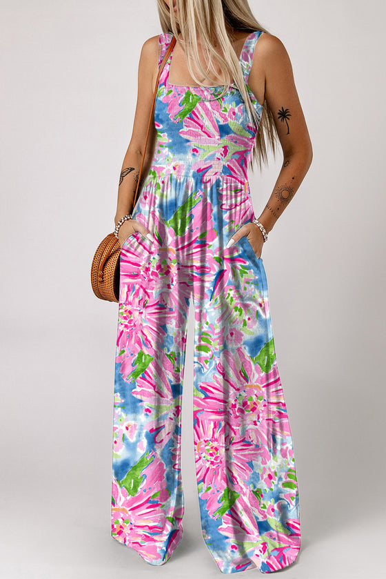 Woman wearing a floral printed sleeveless jumpsuit with a smocked bodice, square neckline, and pockets, perfect for casual chic summer wear.