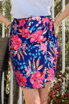 Woman wearing a floral tied mini skirt with a vibrant print and waist tie, ideal for summer days.