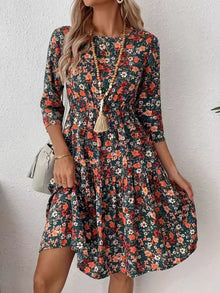  Model wearing a frill floral round neck dress with ruched waist and 3/4 sleeves, styled for an elegant casual outing.

