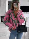 A vibrant geometric-patterned cardigan with dropped shoulders and button closure, styled with casual jeans and a black handbag for a chic winter look.

