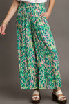 Model wearing the green mixed print pants from the front, showcasing the high-rise fit, relaxed cut, and bold print for a bohemian summer vibe.

