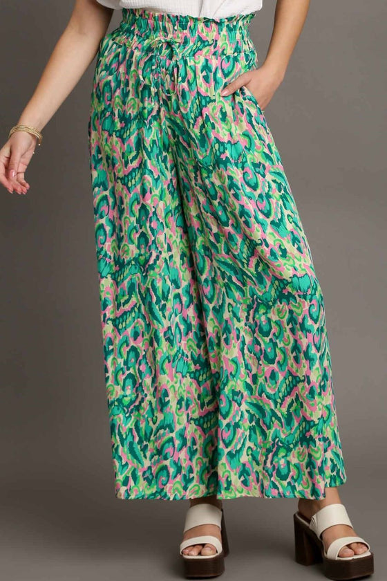 Model wearing the green mixed print pants from the front, showcasing the high-rise fit, relaxed cut, and bold print for a bohemian summer vibe.

