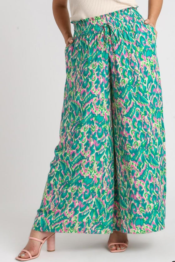 Close shot of the green wide-leg pants from the front, highlighting the mix of geometric and floral prints with soft fabric flow.

