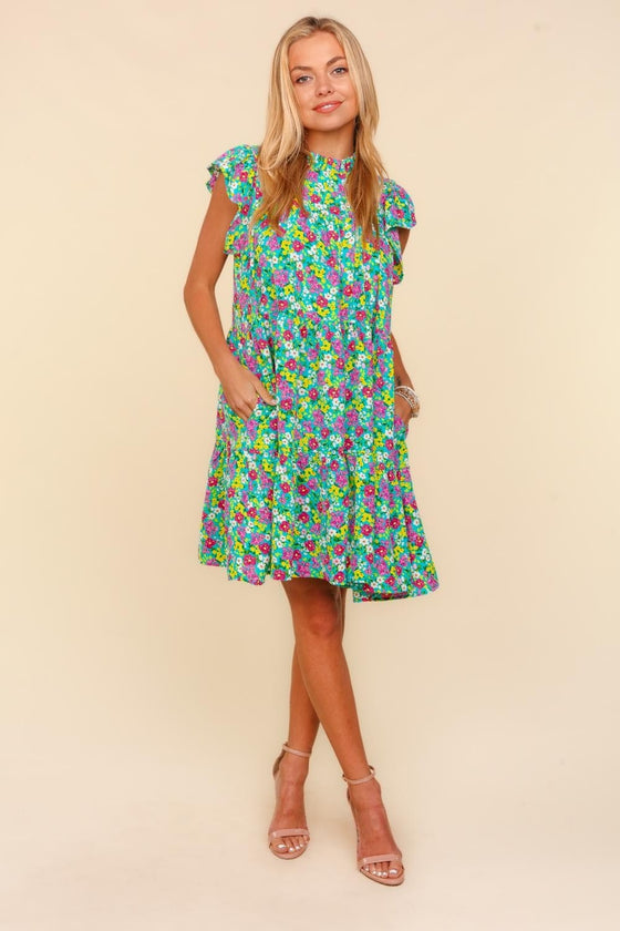 Woman wearing the Haptics Frilled Mock Neck Ditsy Floral Dress with flutter sleeves, tiered design, and a ditsy floral print, perfect for spring occasions.