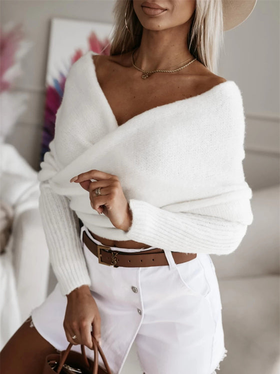 Woman wearing a long sleeve cropped knit top in a neutral beige color, paired with white high-waisted shorts, perfect for a casual outing.

