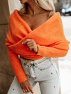 Lifestyle shot of a woman wearing a long sleeve cropped knit top with a stylish belt and accessories.